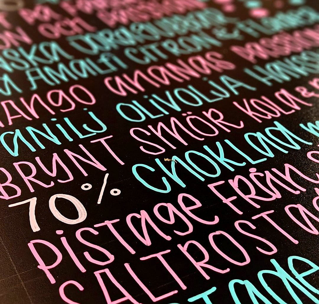 Pink and turquoise pistage lettering on a dark board